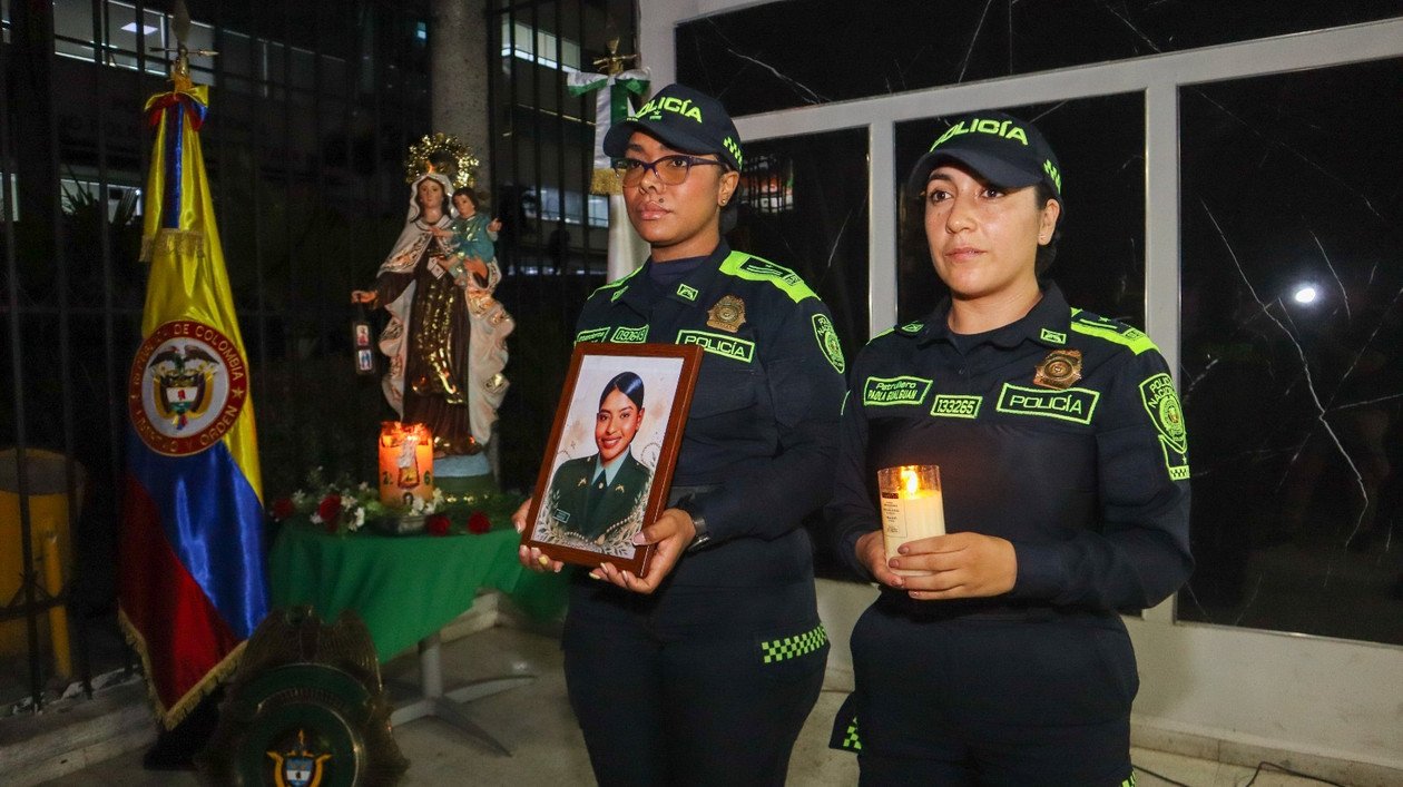 Dos uniformadas sostienen el retrato de la patrullera María José Recuero junto a una vela